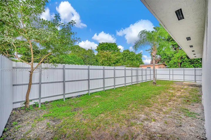 Private rear yard enclosed by white vinyl privacy fencing with a covered patio featuring recessed lighting
