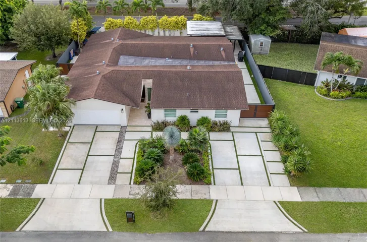 Single-story residence featuring a multi-pitched roofline, expansive concrete paver driveway with integrated turf strips, and drought-tolerant landscaping