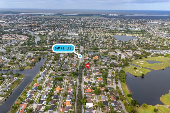 Aerial perspective of a suburban neighborhood featuring mature canopy trees, proximity to inland water bodies, and established street layouts