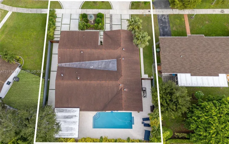 Aerial perspective of property featuring a rectangular swimming pool, expansive concrete patio, multi-section shingle roof, and a paved driveway with integrated landscaping elements