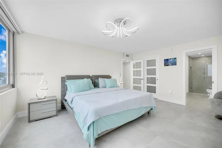 Neutral-toned tile flooring, contemporary multi-arm flush-mount lighting, large-format window, and dual white-framed doors with frosted glass inserts
