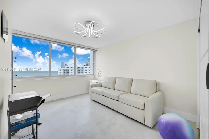 Large-format window featuring expansive coastal scenery, oversized light-colored floor tiles, and a contemporary multi-arm LED light fixture