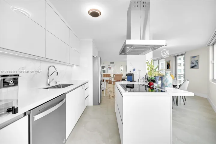 Sleek kitchen featuring high-gloss cabinetry, stone-finish countertops, stainless steel appliances, a center island with a built-in cooktop, and an overhead stainless steel range hood