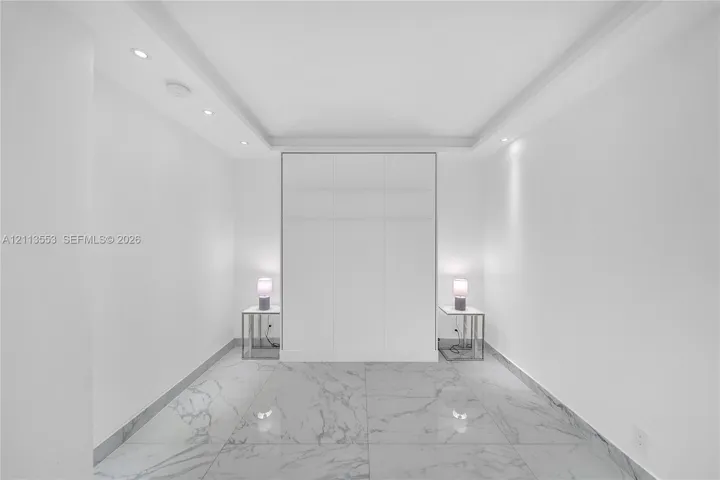 Large-format stone-look flooring, recessed ceiling lighting, tray ceiling architecture, and floor-to-ceiling built-in cabinetry