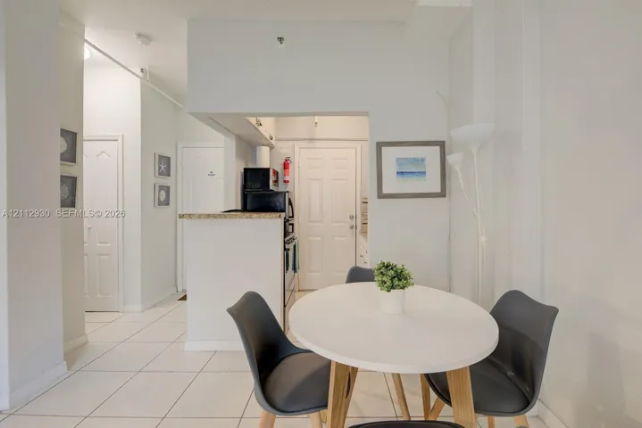 Kitchen featuring a breakfast bar with stone-surfaced countertop, white cabinetry, and ceramic tile flooring