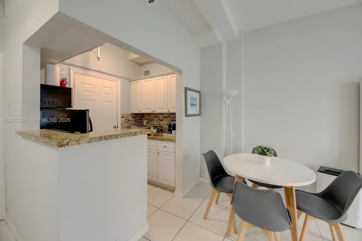 Kitchen featuring white cabinetry, stone-finish countertops, tile backsplash, and light tile flooring