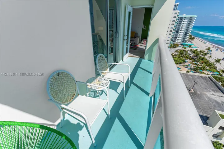 Covered balcony featuring a white railing and sliding glass door entrance