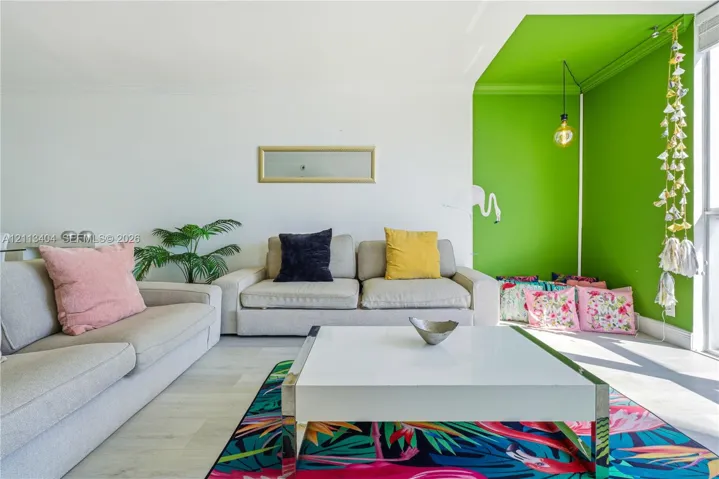 Living area featuring light-toned flooring, recessed ceiling lighting, and a distinct alcove with an accent-painted wall