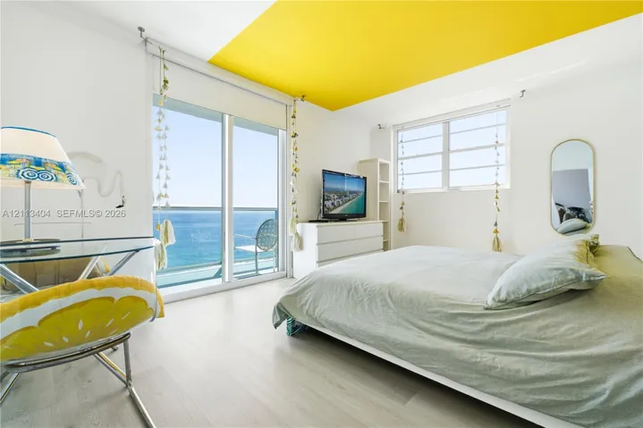 Floor-to-ceiling sliding glass door, white wood-finish flooring, accent-painted ceiling, and horizontal pane windows