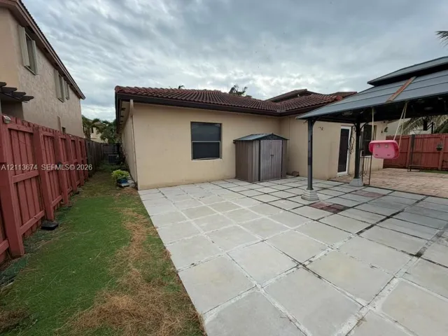 Backyard featuring large-format paver patio, fixed metal gazebo structure, and wood-style perimeter fencing