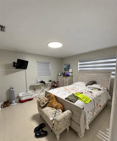 Neutral wall tones, ceramic tile flooring, and dual-layered window shades