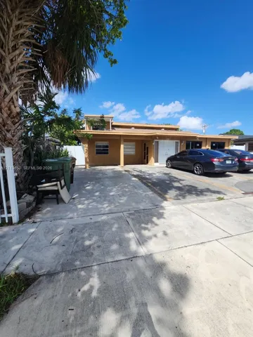 Exterior facade featuring a covered entryway, concrete driveway, and white vinyl perimeter fencing