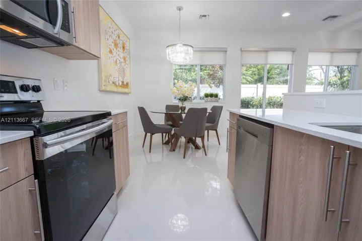 Kitchen featuring light wood-finish cabinetry, white countertops, stainless steel appliances, recessed lighting, and large format tile flooring