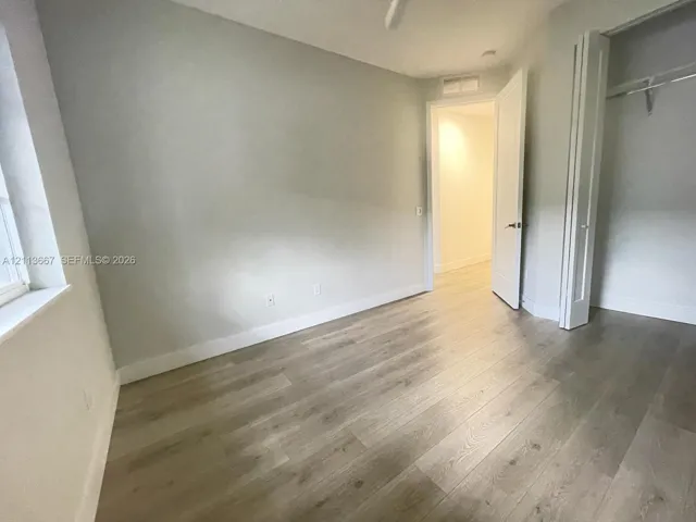 Neutral-toned walls, wood-finish flooring, and a walk-in closet with double-panel doors
