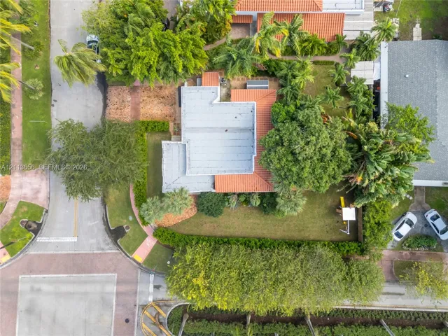 Aerial perspective of a corner lot property featuring a terracotta-tiled roof, mature landscape, and integrated hardscaping