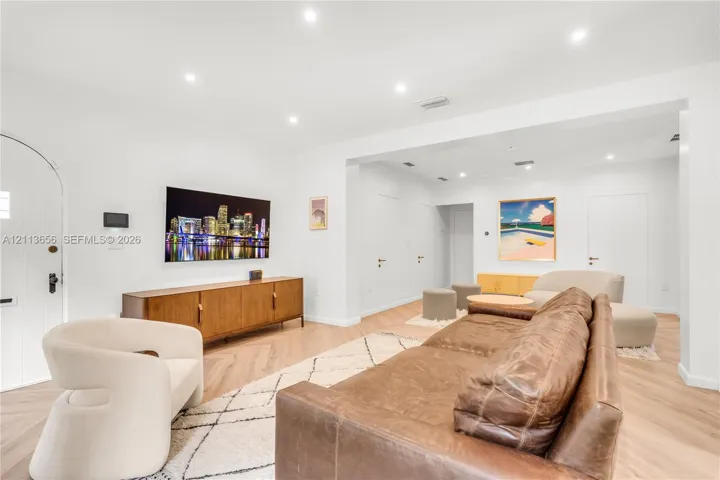 Living area featuring herringbone-pattern wood-finish flooring, recessed lighting, and an arched entry door