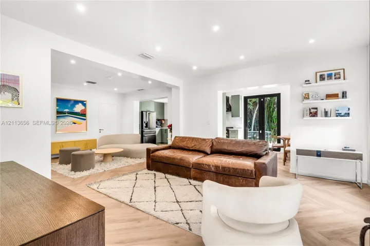 Herringbone-patterned wood-finish flooring, recessed ceiling lighting, and built-in floating wall shelving