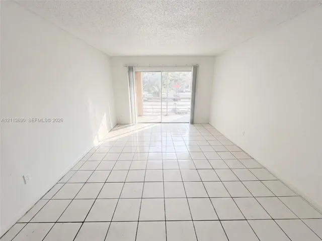 Room featuring white tile flooring and large sliding glass doors