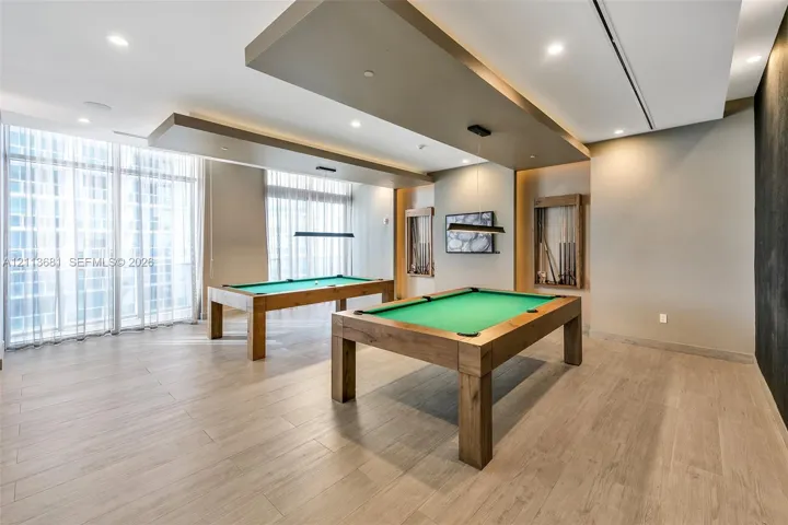 Recessed ceiling panels with integrated lighting, wood-finish tile flooring, floor-to-ceiling windows with curtain tracks, and built-in wall niches