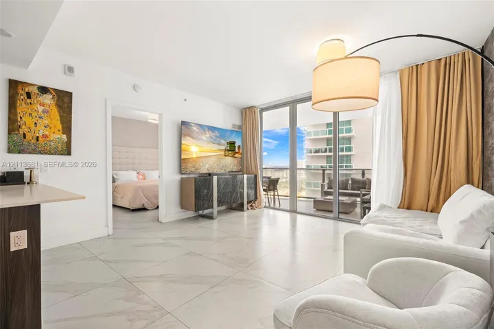 Large-format tile flooring, floor-to-ceiling glass doors, and a private balcony