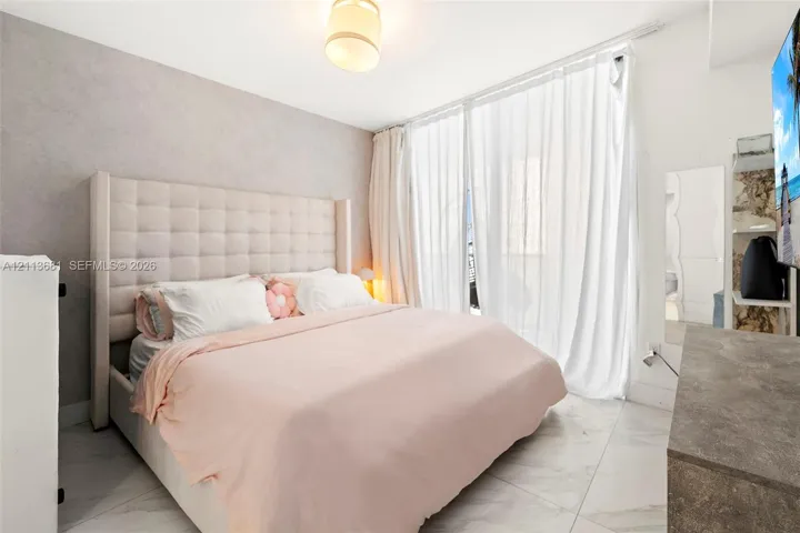 Large-format stone-style flooring, textured accent wall, and floor-to-ceiling glass paneling featuring a neutral-toned drum pendant light fixture
