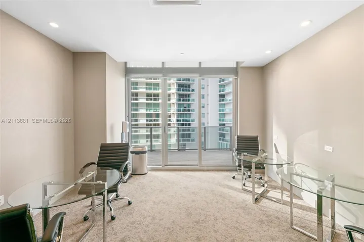 Floor-to-ceiling windows, sliding glass door access to a private balcony, neutral wall-to-wall carpeting, and recessed ceiling lighting
