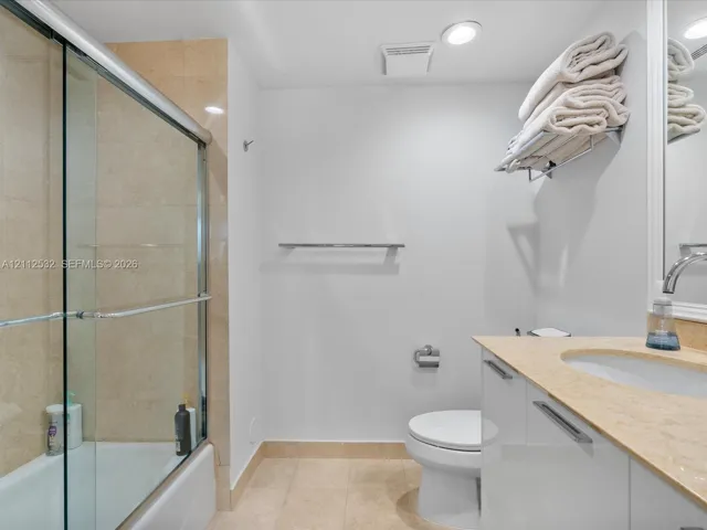 Bathroom featuring a glass-enclosed shower with tiled surround, stone countertop, white vanity cabinetry with chrome hardware, and recessed lighting