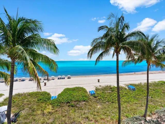 Direct waterfront exposure featuring a sandy beach, turquoise ocean waters, and mature palm trees