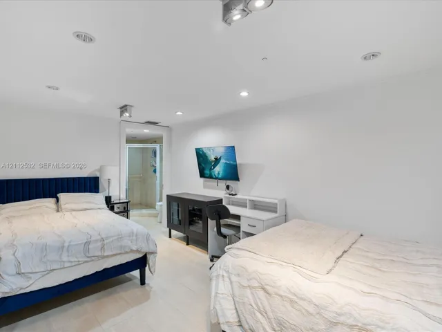 Recessed ceiling lighting, light-toned flooring, and wall-mounted television bracket