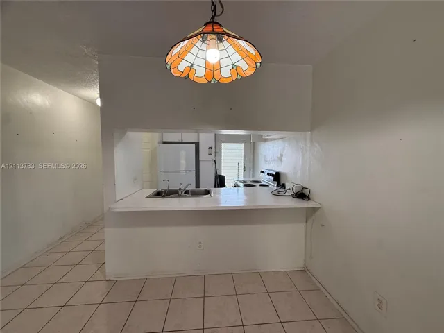 Kitchen pass-through featuring a laminate countertop, dual-basin stainless steel sink, tile flooring, and a decorative stained glass pendant light fixture