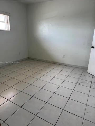 Room featuring neutral wall finishes, ceramic tile flooring, and a single-pane window with top-mounted blind