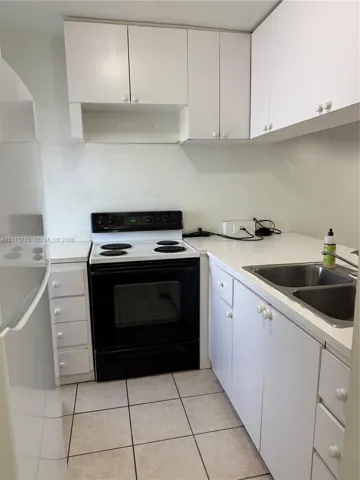 Kitchen featuring white cabinetry, solid surface countertops, stainless steel double basin sink, and a black and white electric range