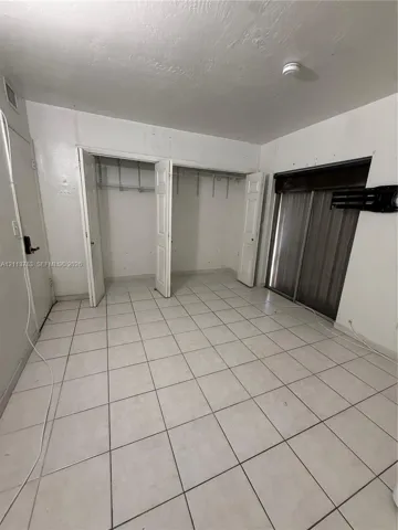 Ceramic tile flooring, double-door closet with built-in shelving, and sliding glass panel doors