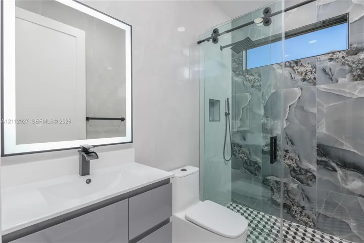 Modern vanity with a rectangular sink, matte black faucet, and backlit mirror