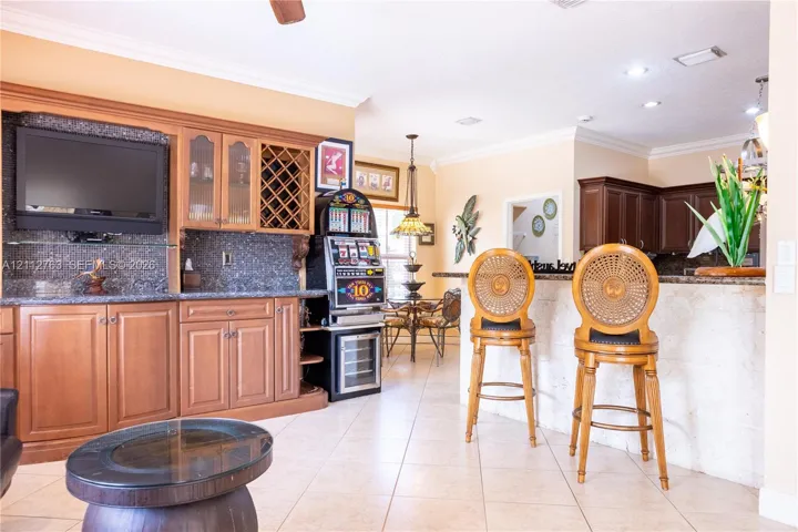 Built-in cabinetry featuring glass-front display panels and wine storage, stone-surfaced bar counter with textured stone base, and tiled flooring