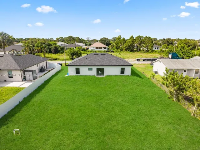 Expansive rear lawn with perimeter vinyl fencing and a dark-toned shingled hip roof