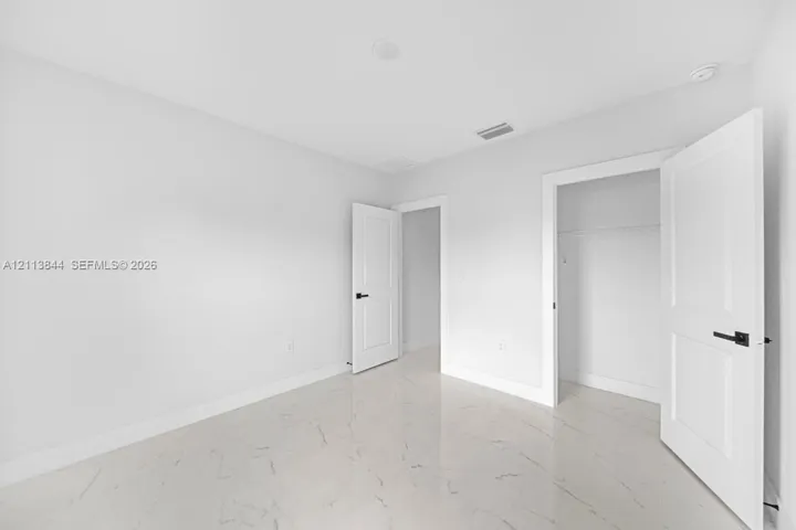 Polished stone-finish tile flooring, white shaker-style interior doors, and matte black lever handles