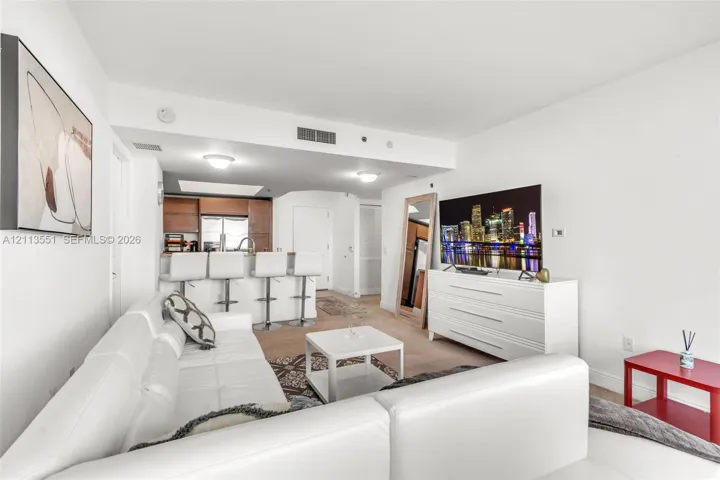 Open-concept living space featuring a breakfast bar with high-top seating, neutral carpeting, recessed ceiling lighting, and wood-finish cabinetry
