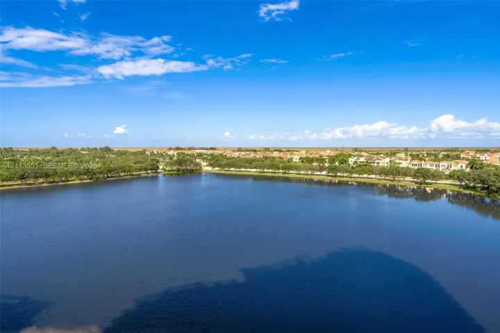 Aerial perspective of a large, open-water lake bordered by mature trees and residential development