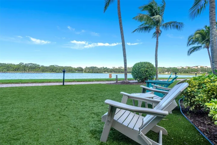 Waterfront lawn area featuring a manicured grass surface, mature palm trees, and ground-level landscape lighting