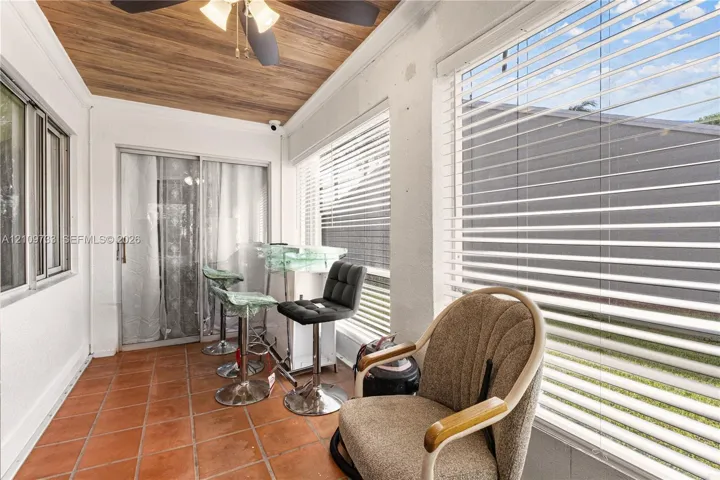 Enclosed patio featuring terra-cotta tile flooring, wood-finish ceiling paneling, a mounted ceiling fan, and large-format horizontal windows