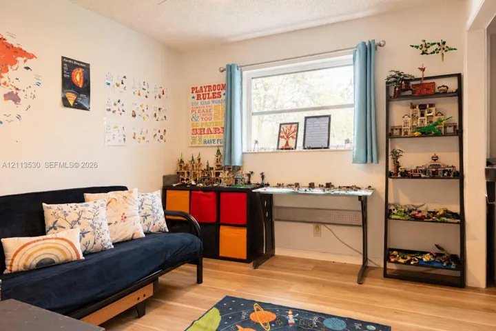 Neutral-toned interior space featuring wood-finish flooring and a horizontal picture window with brushed nickel curtain rod hardware