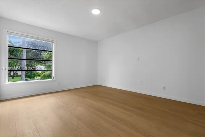 Bright room featuring wood-finish flooring, a multi-pane horizontal window, and recessed ceiling lighting