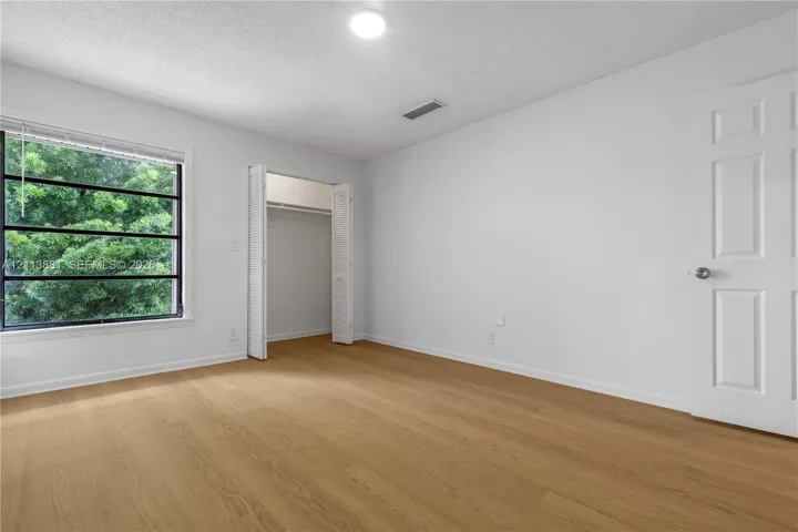 Wood-finish flooring, multi-pane window with exterior greenery, and bi-fold closet doors