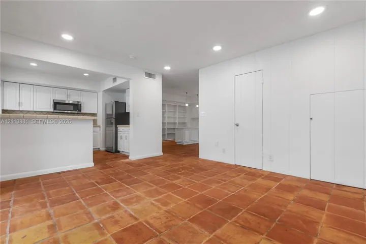 Interior space featuring terra-cotta tile flooring, recessed lighting, and built-in white cabinetry with a breakfast bar
