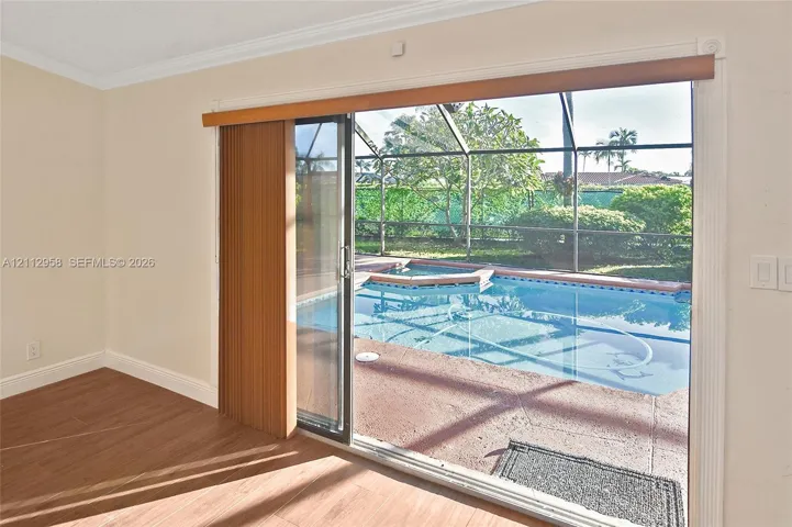 Sliding glass door opening to a screened-in patio featuring a swimming pool, spa, and tile flooring