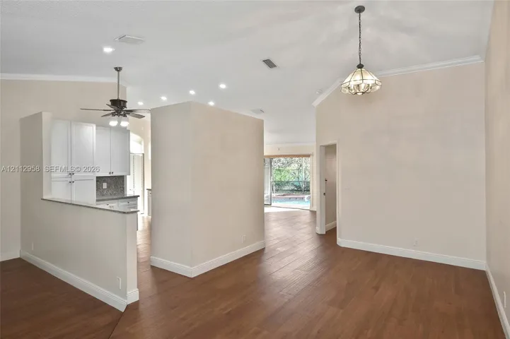 Vaulted ceilings featuring recessed lighting, wood-finish flooring, white cabinetry, and multi-light fixtures