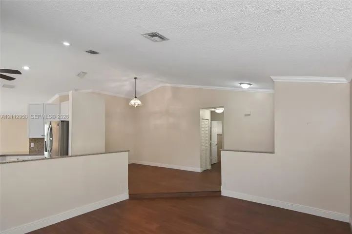 Vaulted ceilings, wood-finish flooring, recessed lighting, and partial height partition walls with stone-surface counters