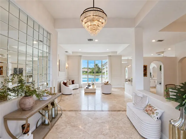 Foyer featuring large-scale polished stone flooring, a multi-tiered crystal chandelier, and a floor-to-ceiling grid-patterned wall mirror