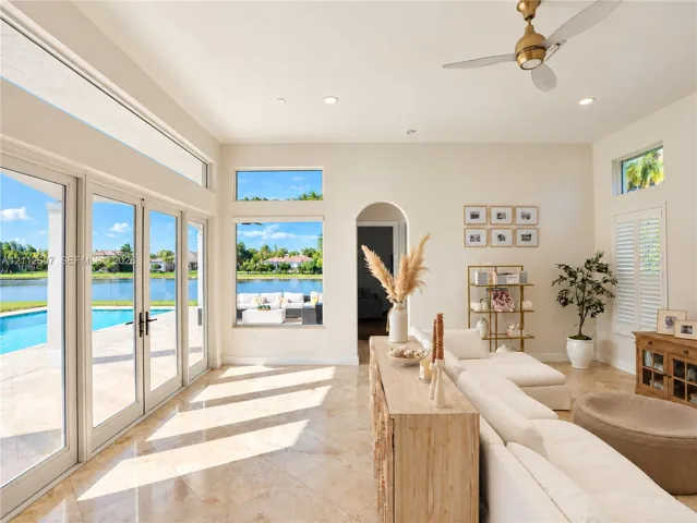 Large-format windows, multi-panel glass patio doors, recessed lighting, arched entryway, and stone-finish flooring
